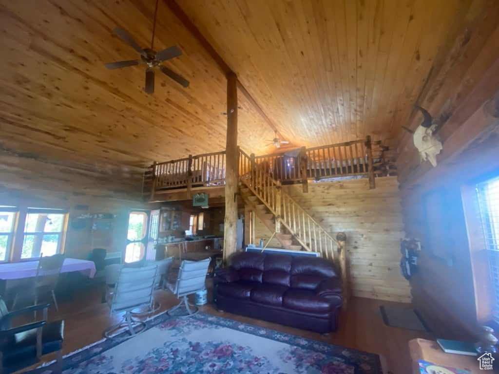 Living room featuring wood walls, ceiling fan, wooden ceiling, lofted ceiling, and hardwood / wood-style flooring