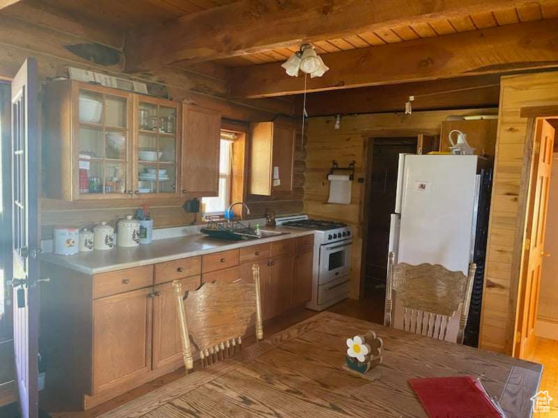 Kitchen featuring beamed ceiling, white appliances, light hardwood / wood-style flooring, sink, and wood ceiling