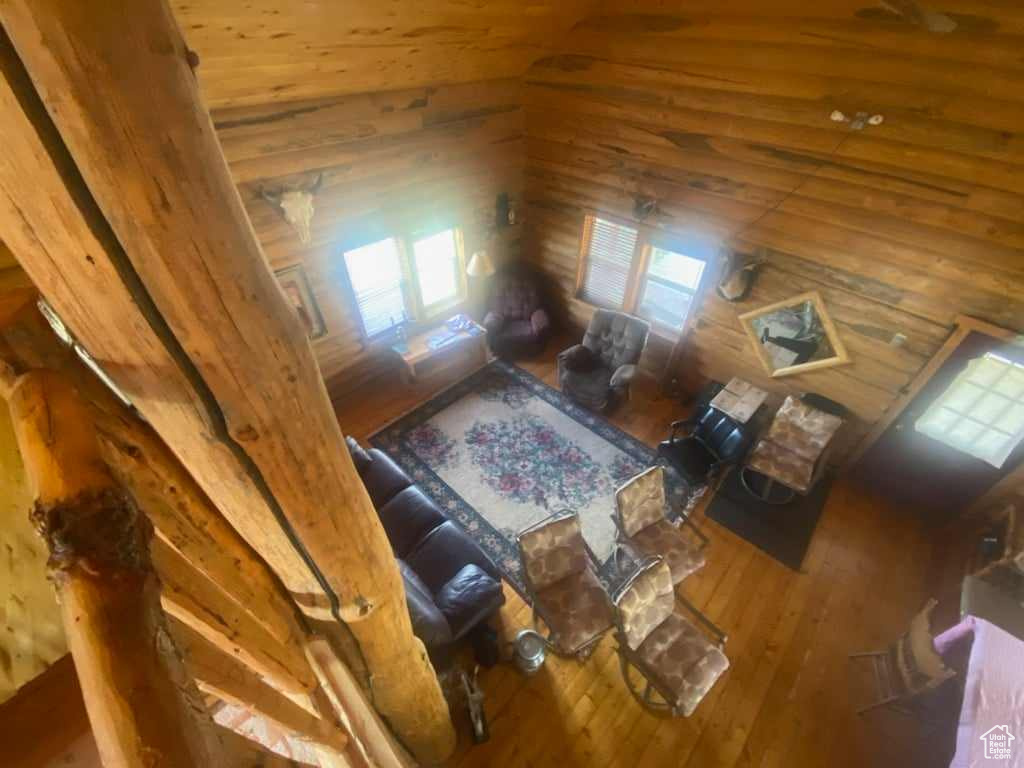 Living room featuring wood walls, hardwood / wood-style floors, and high vaulted ceiling