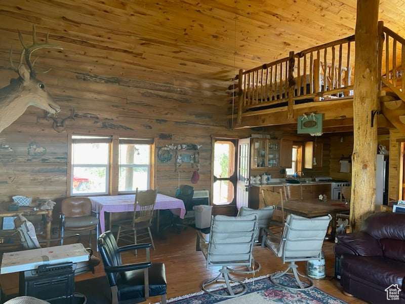 Living room featuring wood-type flooring, wooden walls, and a towering ceiling