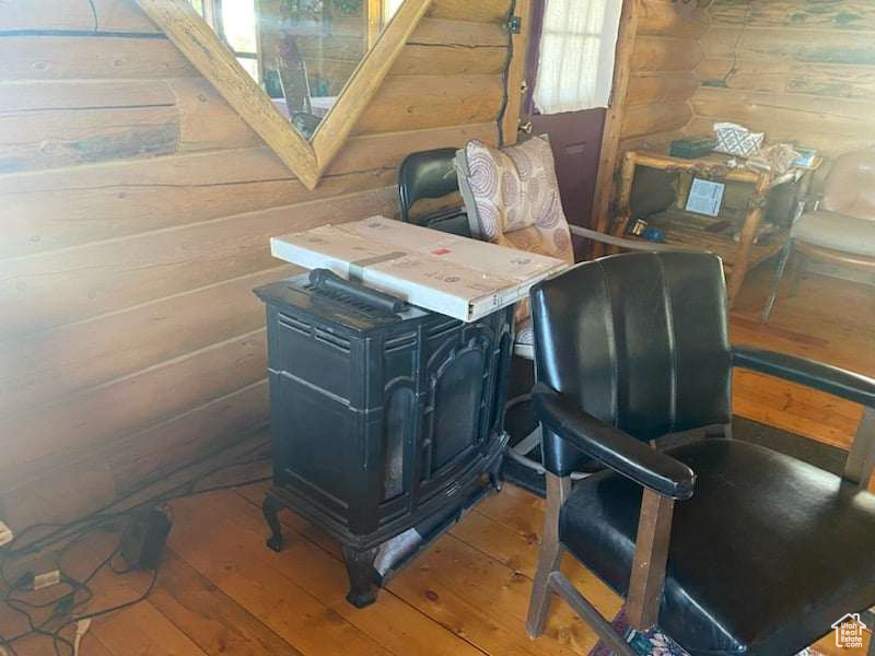 Office with a wood stove, wood-type flooring, and wooden walls