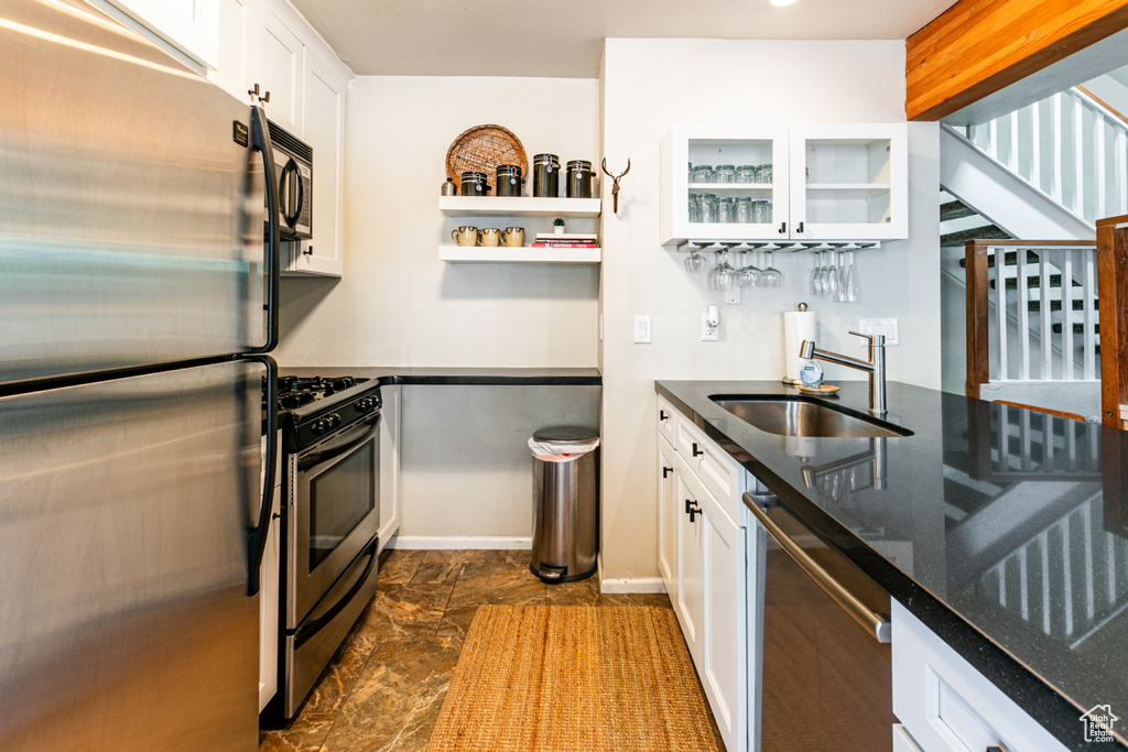 Kitchen with dark stone countertops, sink, appliances with stainless steel finishes, and white cabinetry