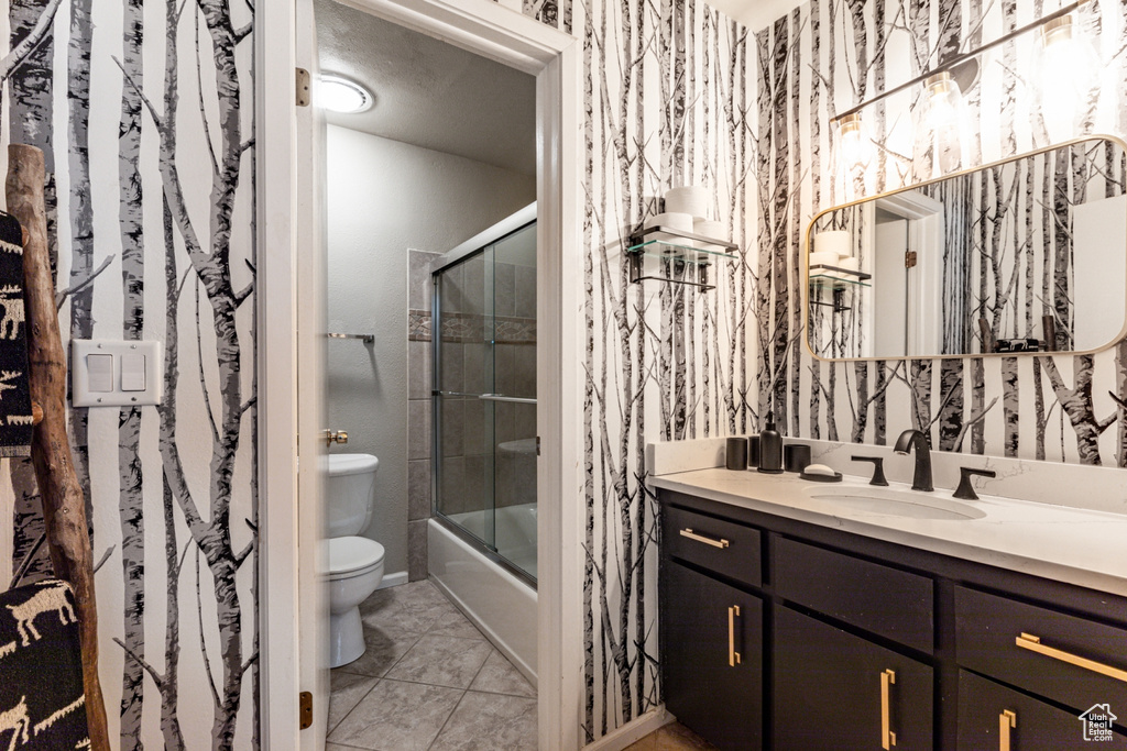 Full bathroom featuring shower / bath combination with glass door, vanity, toilet, and tile patterned flooring