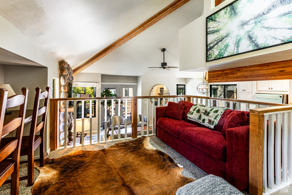 Carpeted living room featuring lofted ceiling with beams and ceiling fan