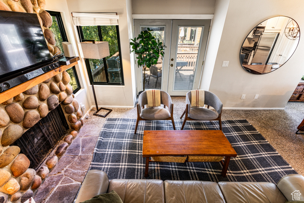 Carpeted living room featuring a stone fireplace and french doors