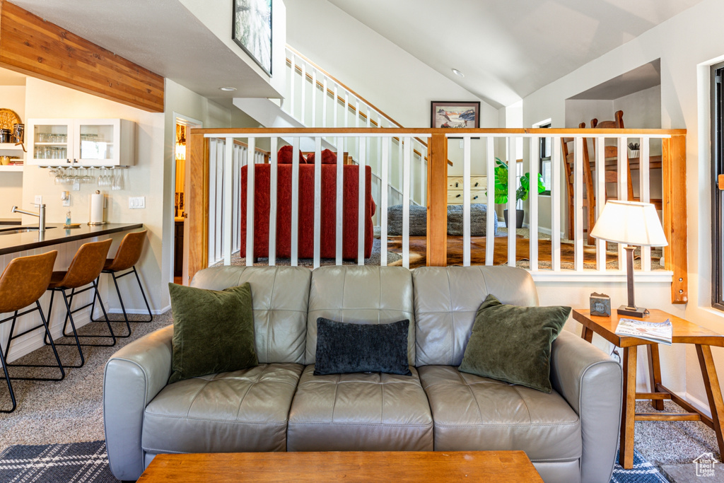 Living room featuring carpet flooring, lofted ceiling with beams, and wet bar