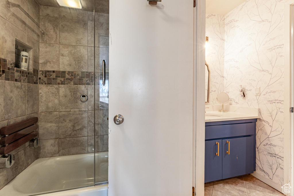 Bathroom featuring tile patterned floors, shower / bath combination with glass door, and vanity