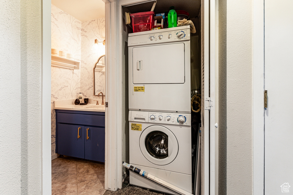 Washroom with light tile patterned floors, sink, and stacked washer / dryer