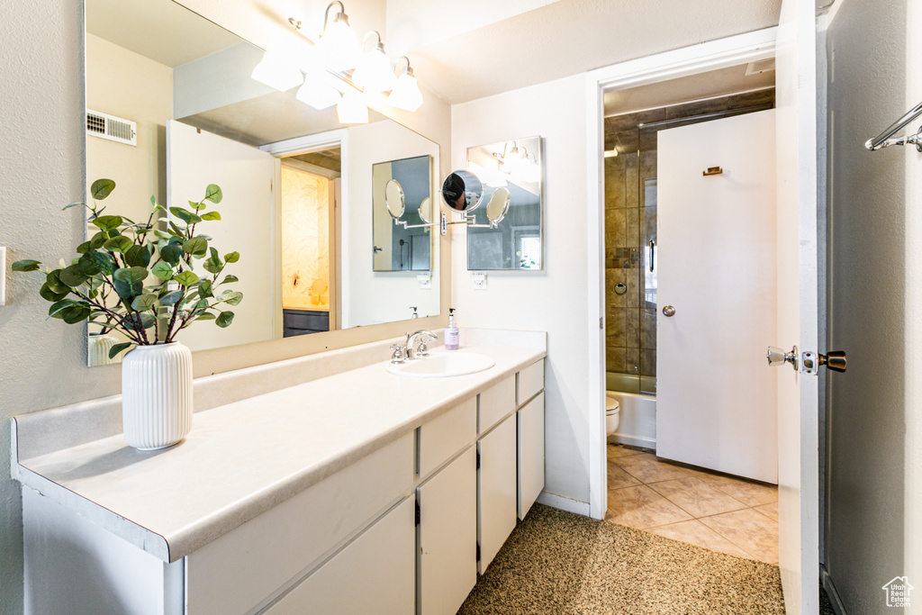 Full bathroom with toilet, tile patterned flooring, vanity, a chandelier, and tiled shower / bath combo