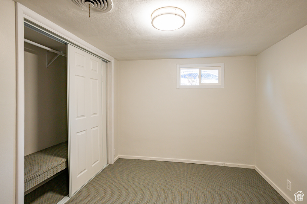 Unfurnished bedroom featuring a closet, a textured ceiling, and carpet