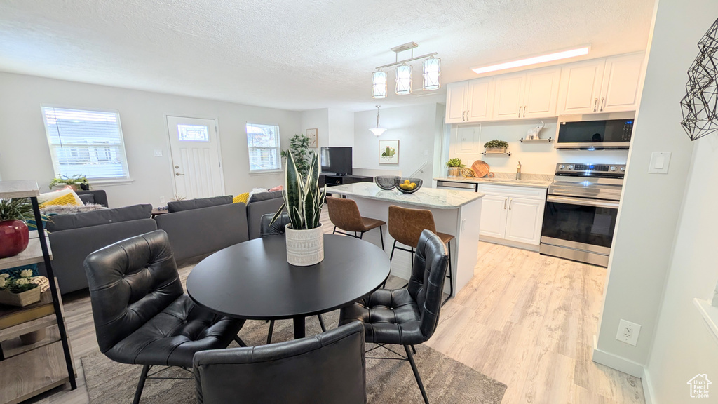 Dining area with sink, light wood-type flooring, and a textured ceiling