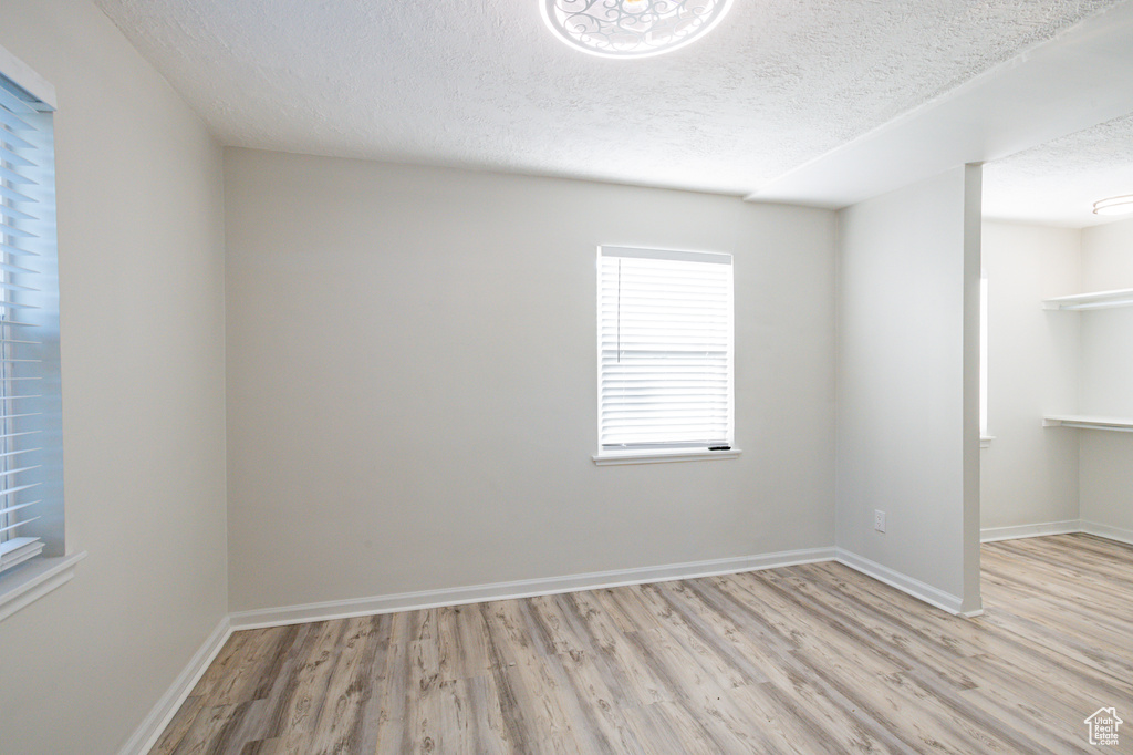 Spare room with a textured ceiling and light hardwood / wood-style flooring