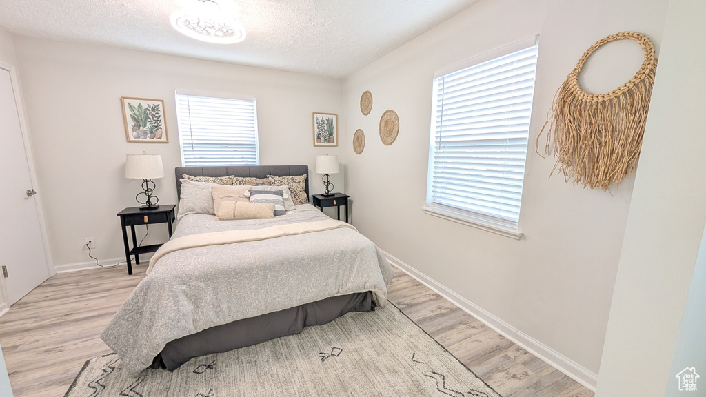 Bedroom featuring multiple windows, light hardwood / wood-style flooring, and a textured ceiling