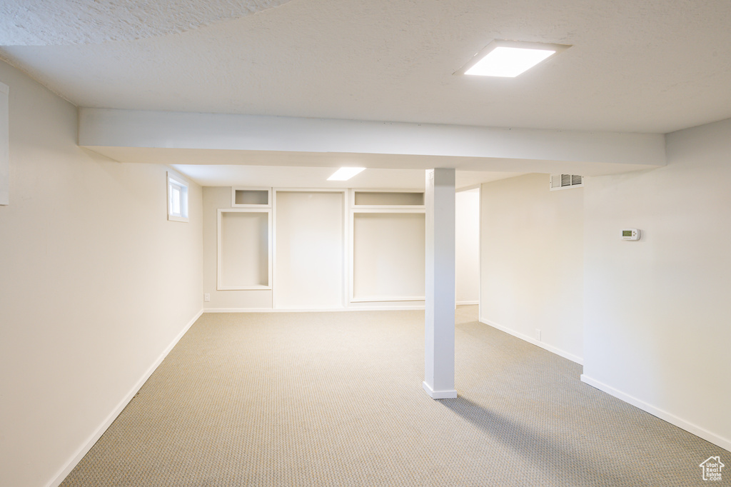 Basement with a textured ceiling and carpet