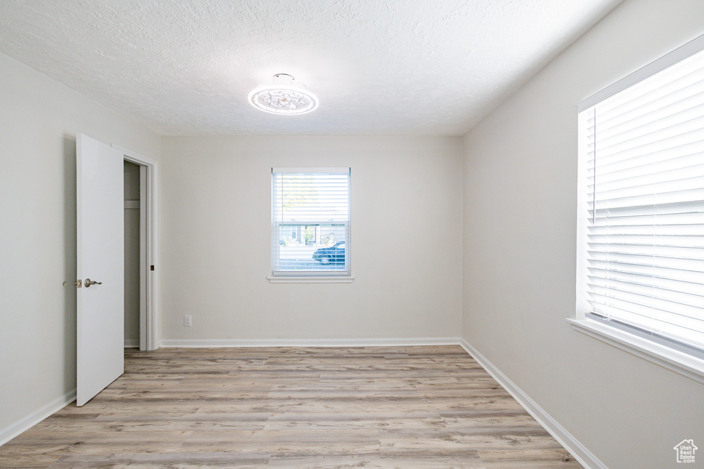 Spare room with a textured ceiling and light hardwood / wood-style flooring