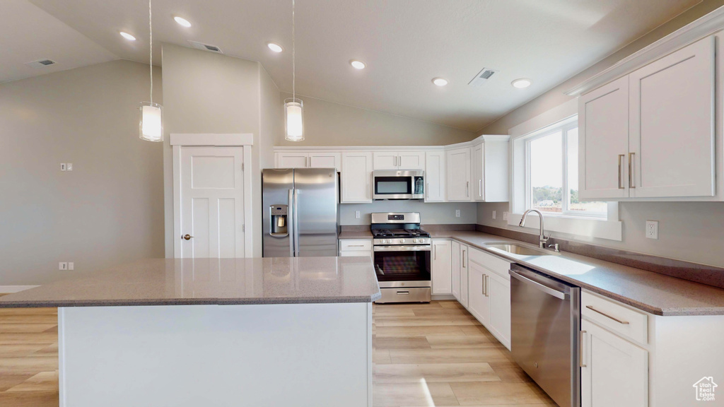 Kitchen featuring decorative light fixtures, stainless steel appliances, light hardwood / wood-style floors, white cabinetry, and sink