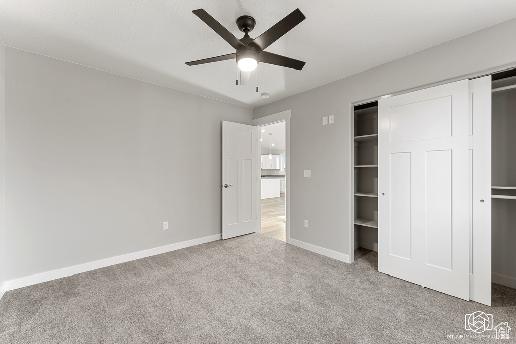 Unfurnished bedroom with ceiling fan, light colored carpet, and a closet