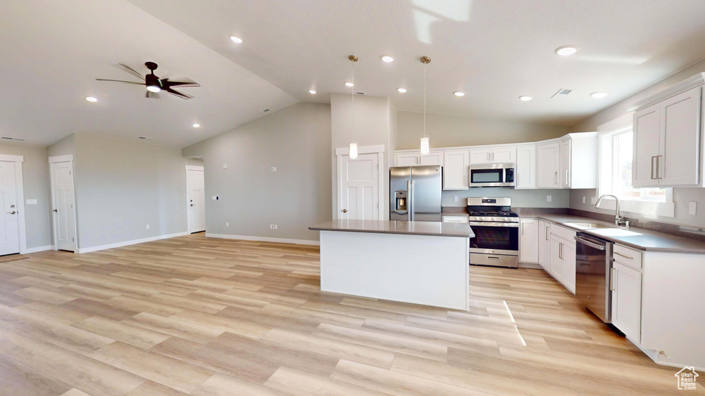 Kitchen featuring stainless steel appliances, a center island, ceiling fan, sink, and white cabinets