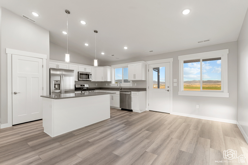 Kitchen with pendant lighting, white cabinets, a kitchen island, light hardwood / wood-style flooring, and appliances with stainless steel finishes