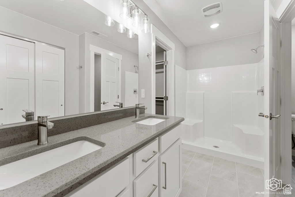 Bathroom with vanity, a shower, and tile patterned flooring