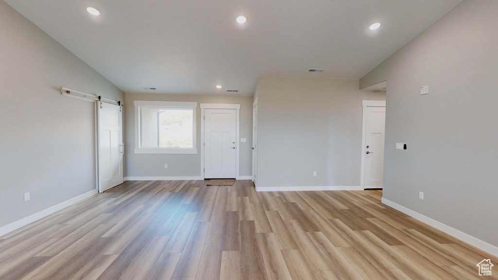 Unfurnished room with a barn door and light hardwood / wood-style floors