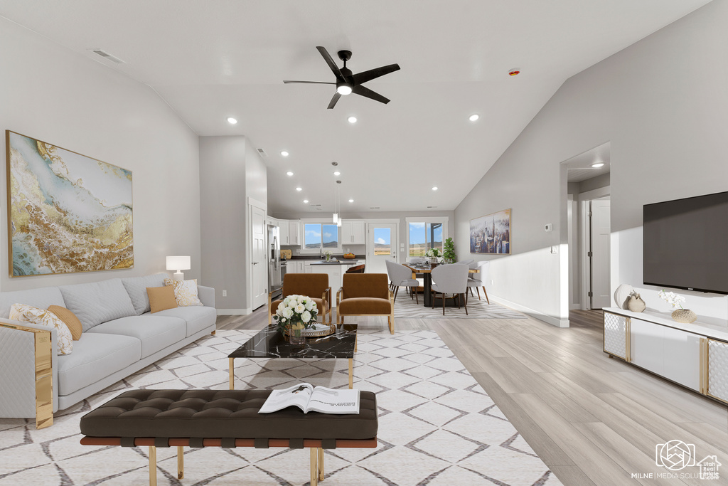 Living room with light wood-type flooring, ceiling fan, and high vaulted ceiling