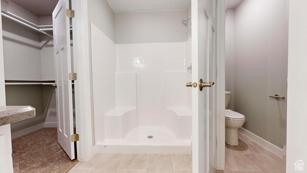 Bathroom with tile patterned flooring, a shower, and toilet