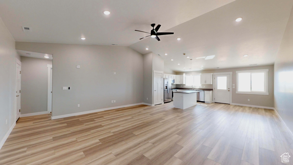 Unfurnished living room with lofted ceiling, ceiling fan, and light hardwood / wood-style floors