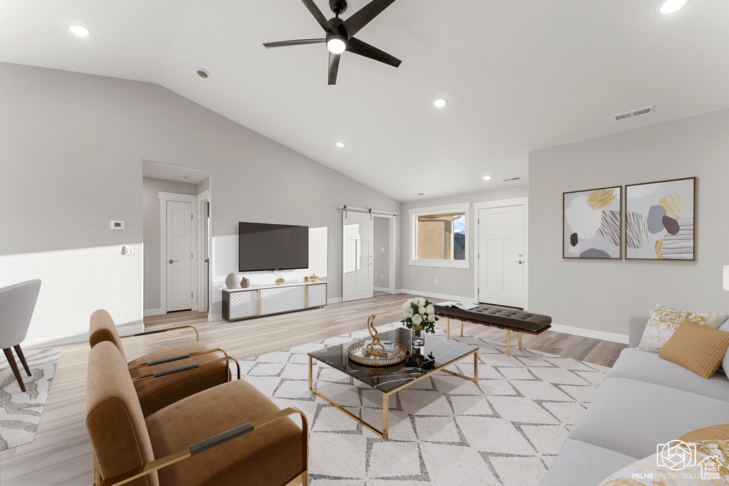 Living room with a barn door, vaulted ceiling, ceiling fan, and light hardwood / wood-style flooring