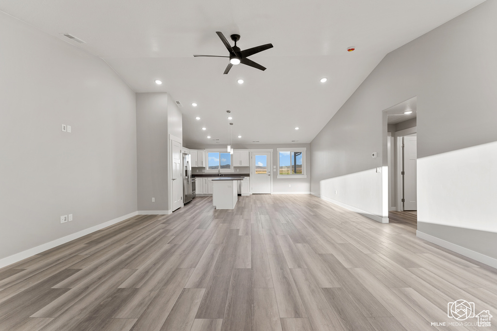 Unfurnished living room with lofted ceiling, light hardwood / wood-style floors, and ceiling fan