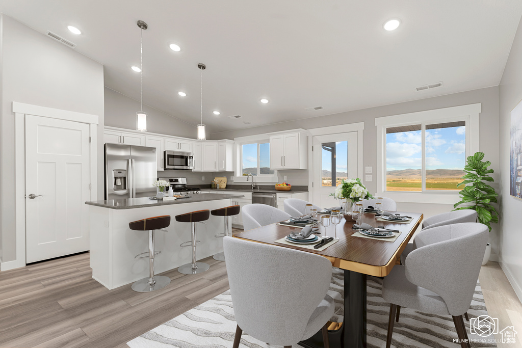 Dining space featuring vaulted ceiling and light hardwood / wood-style flooring