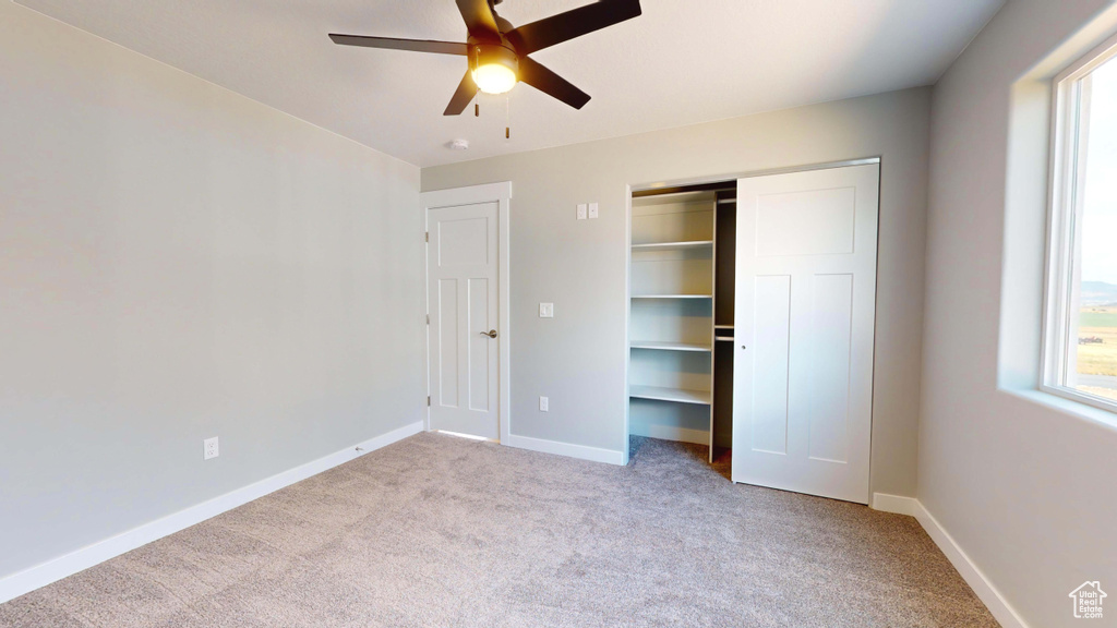 Unfurnished bedroom with a closet, ceiling fan, and light carpet