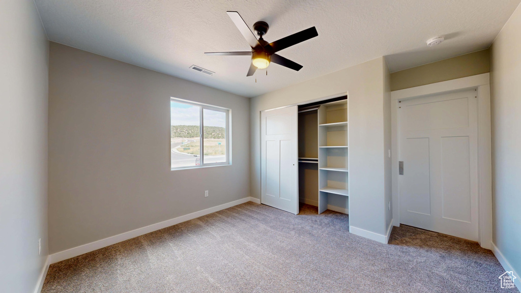 Unfurnished bedroom with a closet, ceiling fan, light carpet, and a textured ceiling