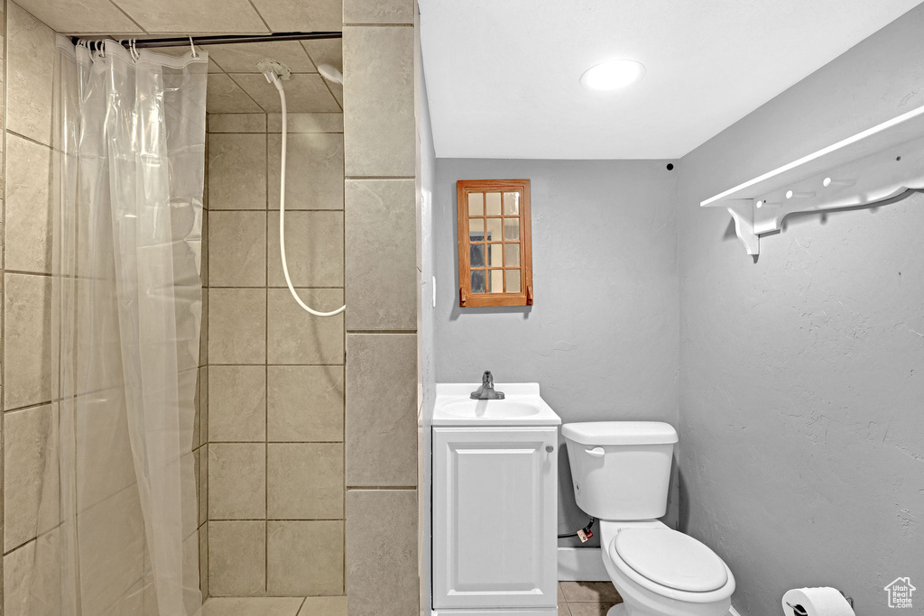 Bathroom featuring vanity, toilet, curtained shower, and tile patterned floors