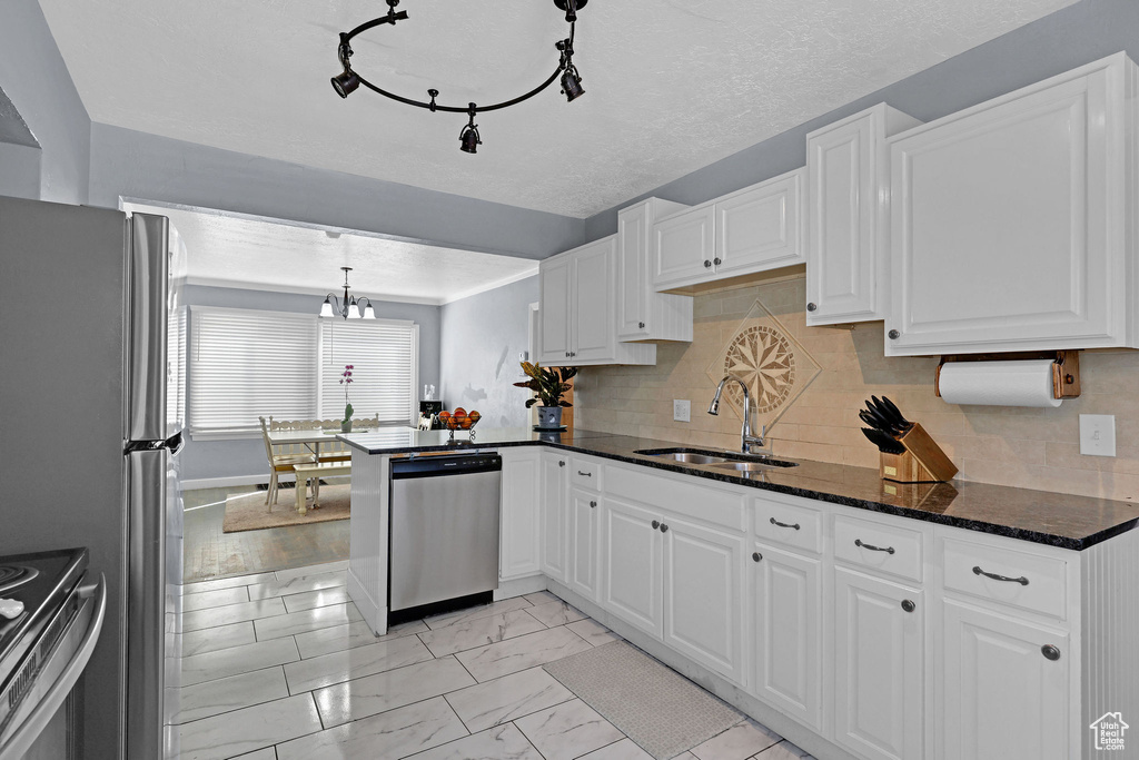 Kitchen featuring white cabinetry, light wood-type flooring, appliances with stainless steel finishes, and dark stone counters