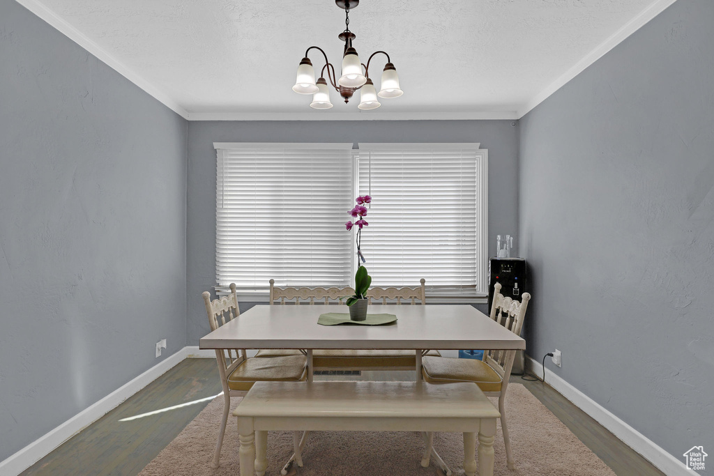 Dining area with dark hardwood / wood-style floors, a notable chandelier, and ornamental molding