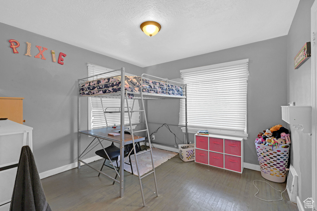 Bedroom featuring dark wood-type flooring, multiple windows, and a textured ceiling