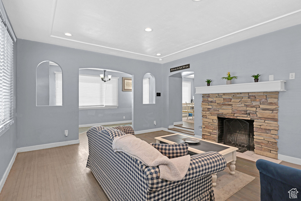 Living room featuring hardwood / wood-style floors, a notable chandelier, and a stone fireplace