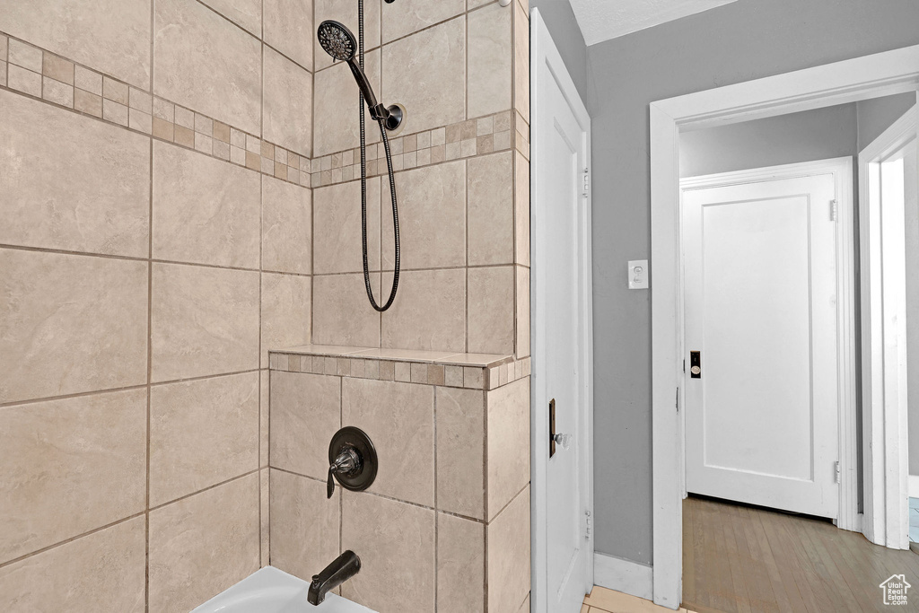 Bathroom featuring tiled shower / bath and wood-type flooring