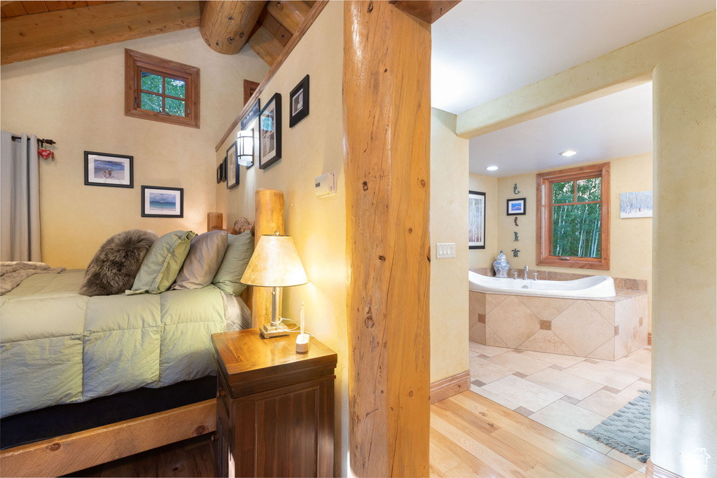 Bedroom featuring light wood-type flooring and vaulted ceiling with beams