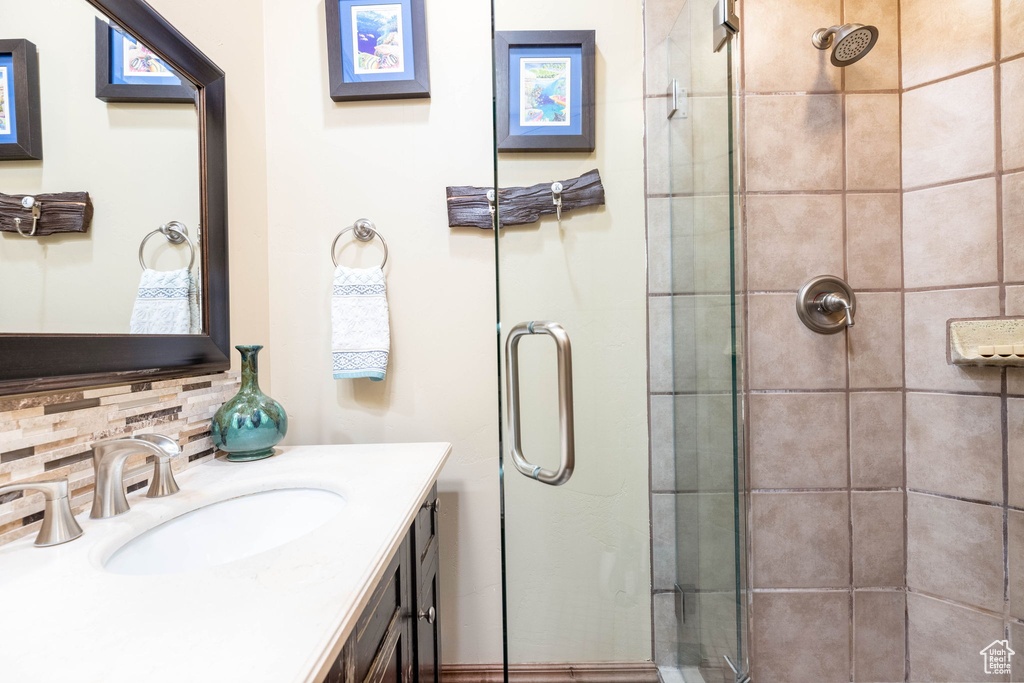 Bathroom featuring vanity, an enclosed shower, and decorative backsplash