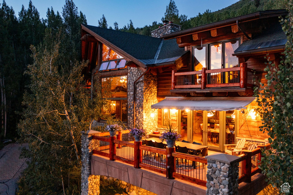 Back house at dusk featuring a balcony and a deck