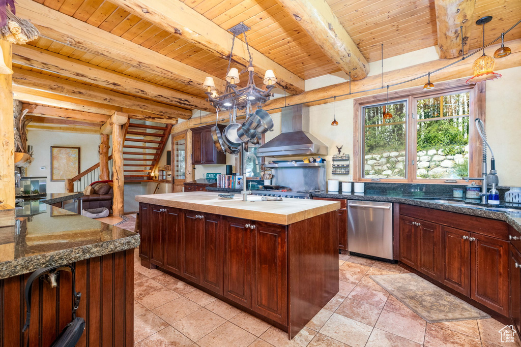 Kitchen featuring an island with sink, stainless steel dishwasher, beamed ceiling, and wall chimney range hood