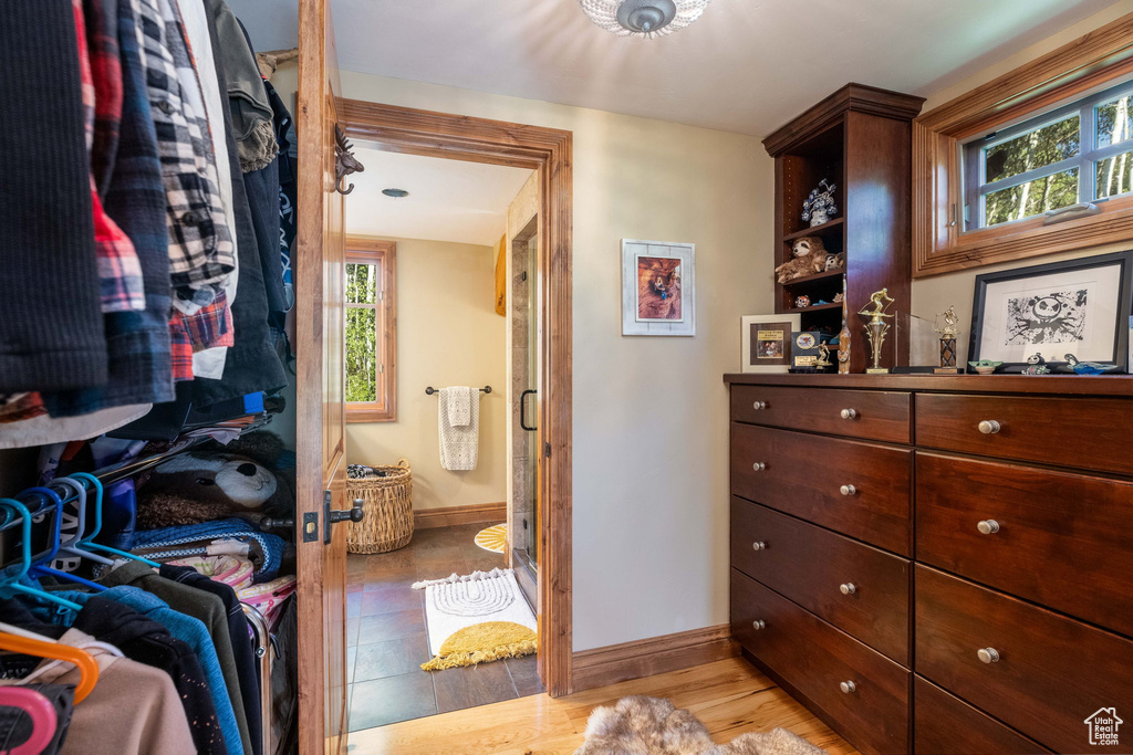 Walk in closet with light hardwood / wood-style floors