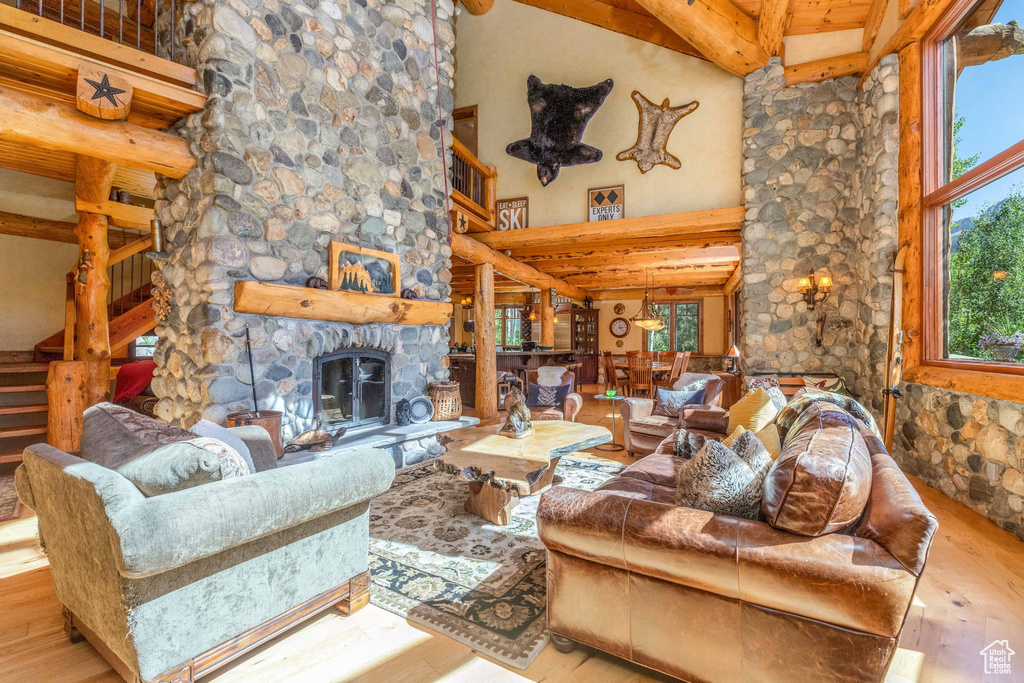 Living room with a towering ceiling, beam ceiling, hardwood / wood-style flooring, and a fireplace