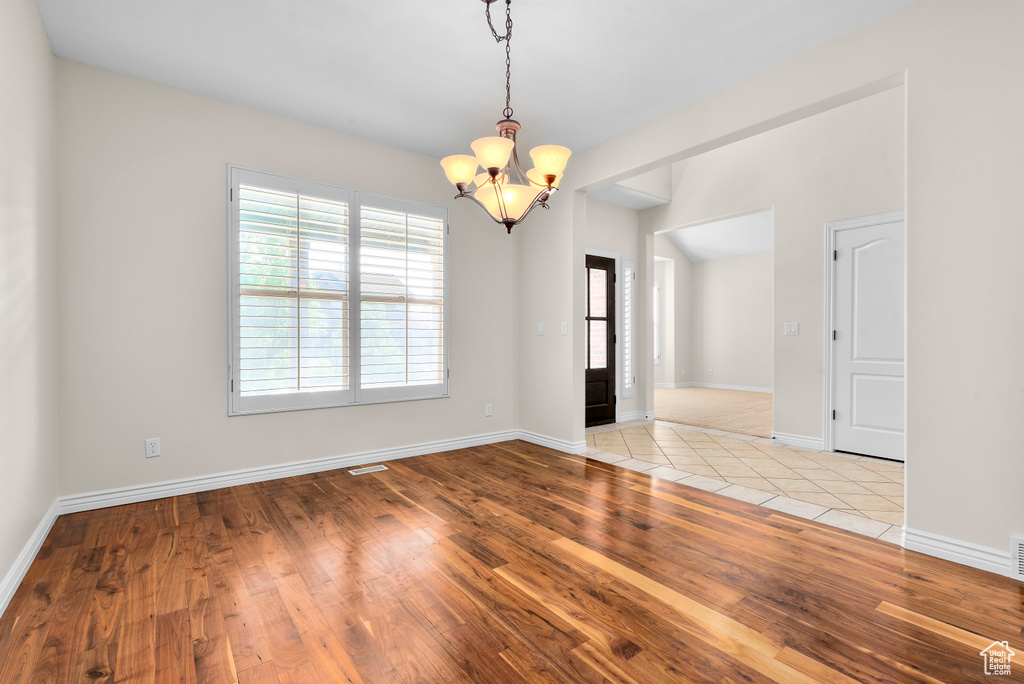 Spare room with light wood-type flooring and a chandelier