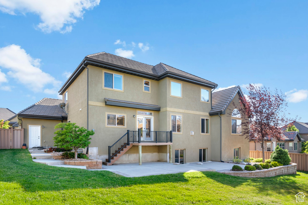 Rear view of property featuring a lawn and a patio area