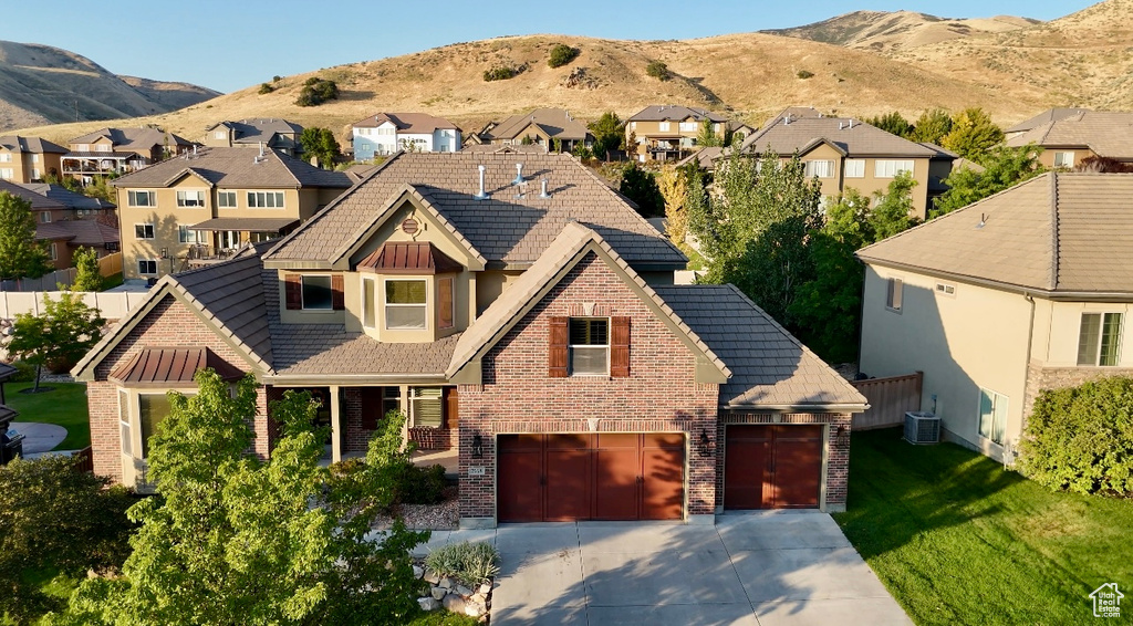 View of front of home with cooling unit, a garage, and a mountain view