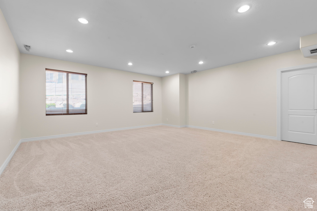 Unfurnished room with light colored carpet and a wall mounted air conditioner