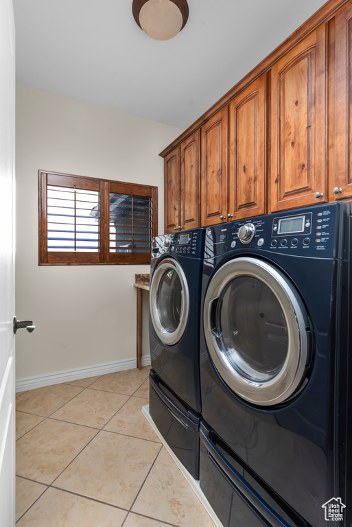 Laundry area featuring separate washer and dryer, cabinets, and light tile patterned flooring